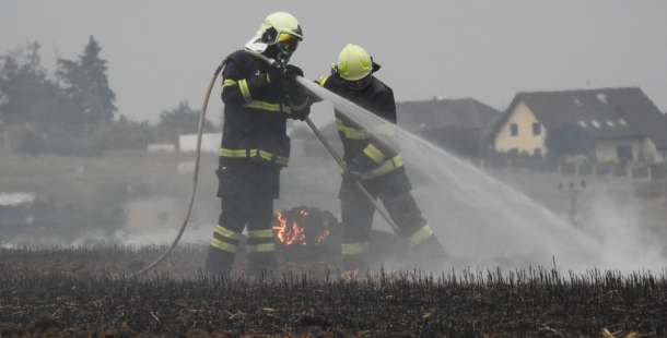 Deset hasičských jednotek likviduje požár pole u Podluh. Vítr hnal oheň do lesa