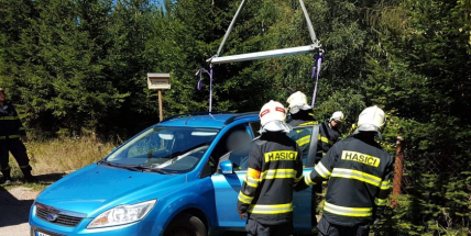 Nepozorný řidič se svým vozidlem skončil napůl v příkopu, ven mu pomáhají hasiči s jeřábem